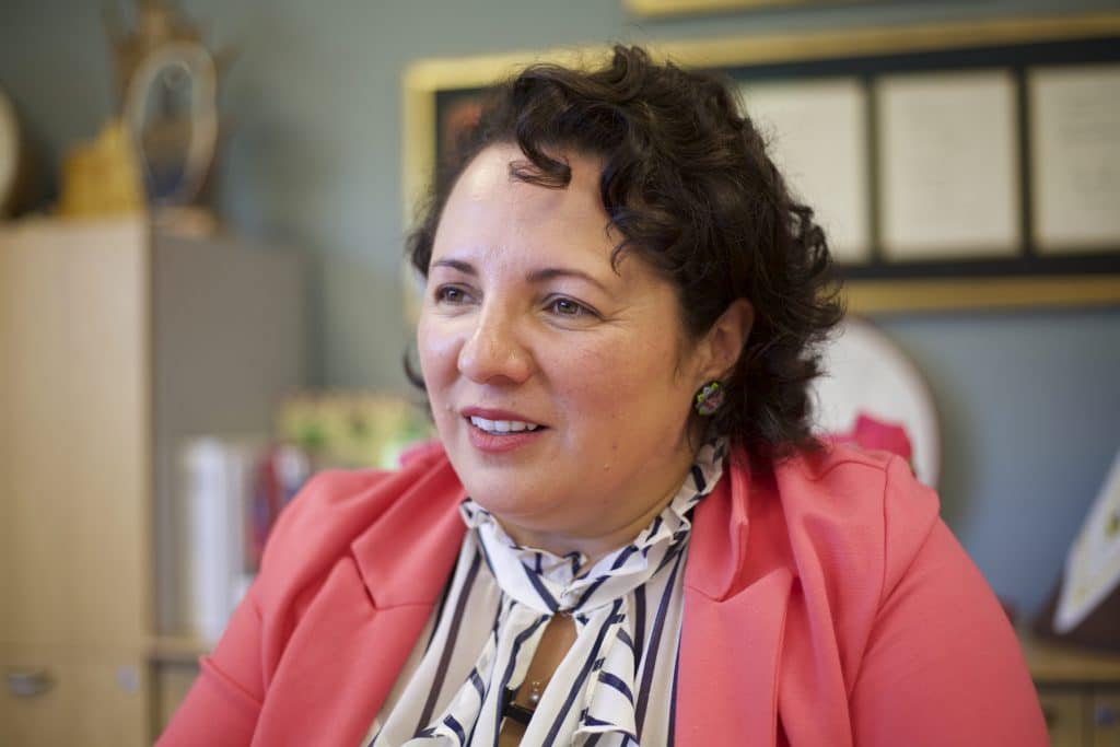 A woman speaking, looking at someone just off-camera